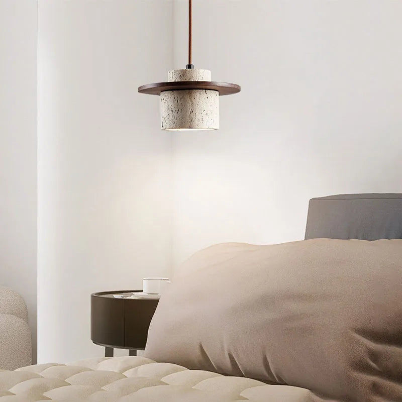 Luminária Pendente Hano em travertino natural com disco de madeira escura, pendurada ao lado da cama